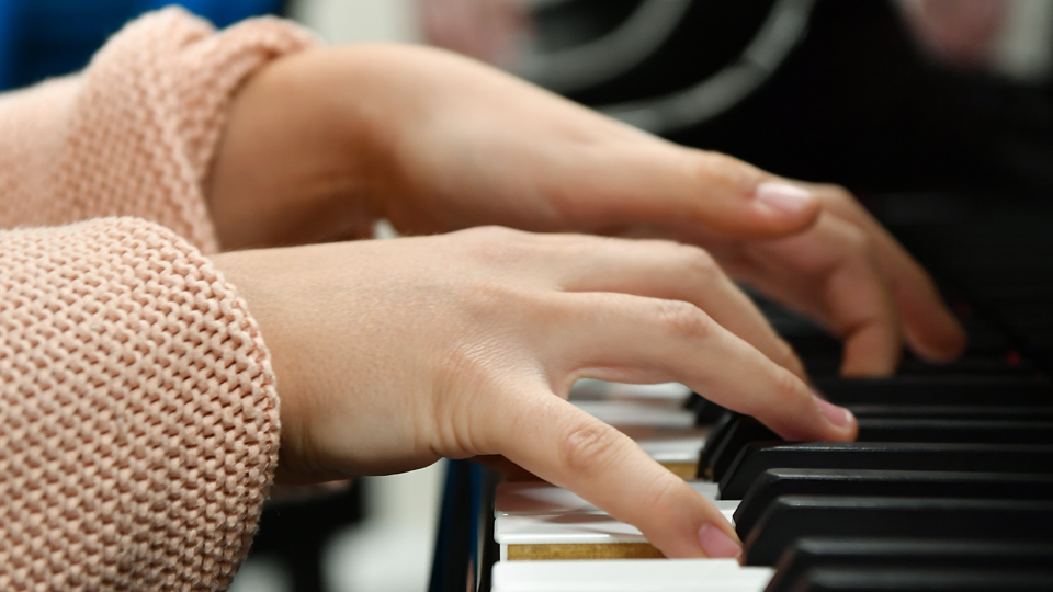 A pianists fingers on the keys of the instrument
